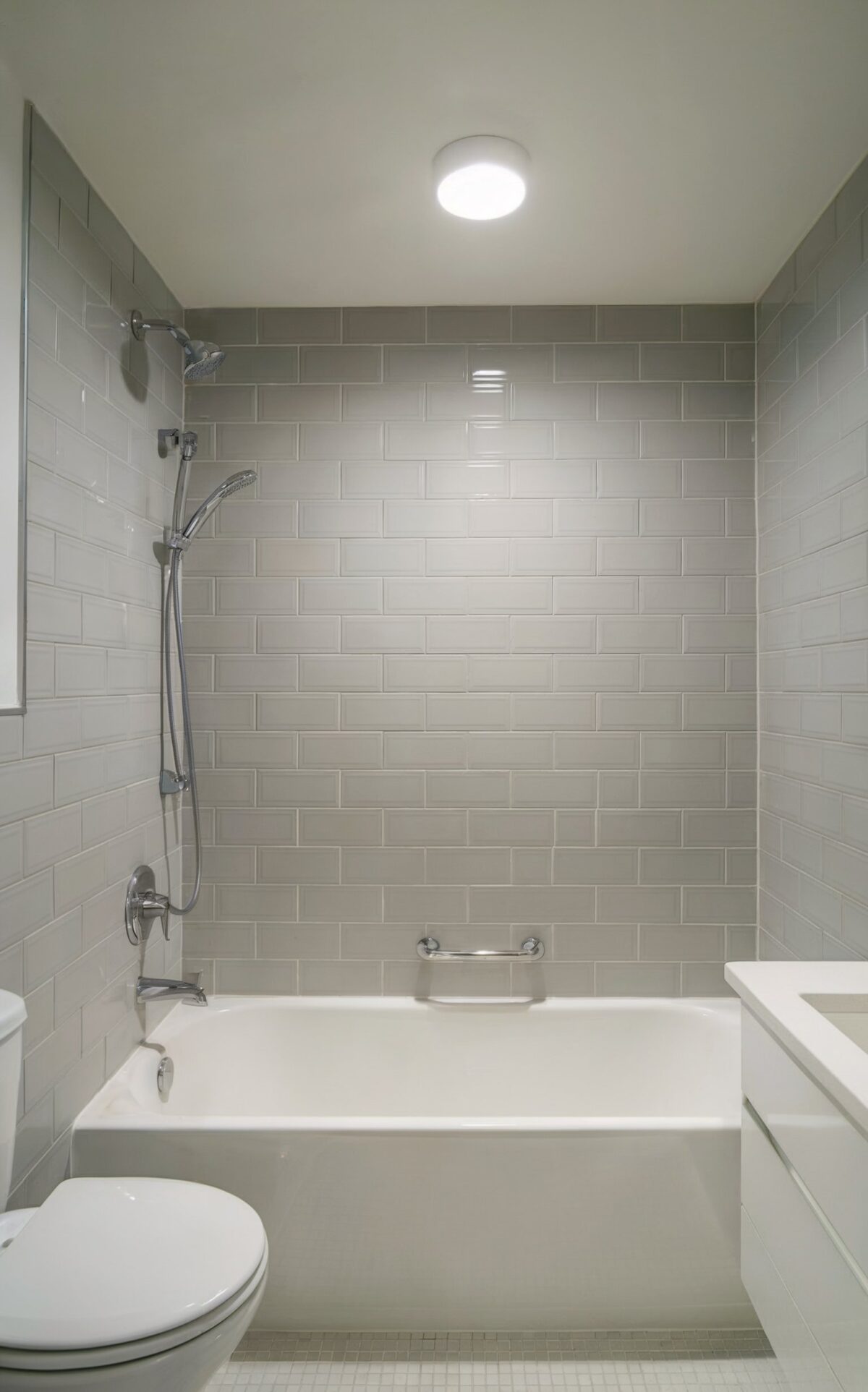 coastal gray tile bathroom ideas A photo of a modern bathroom with a dominant light gray tile wall that surrounds a white bathtub