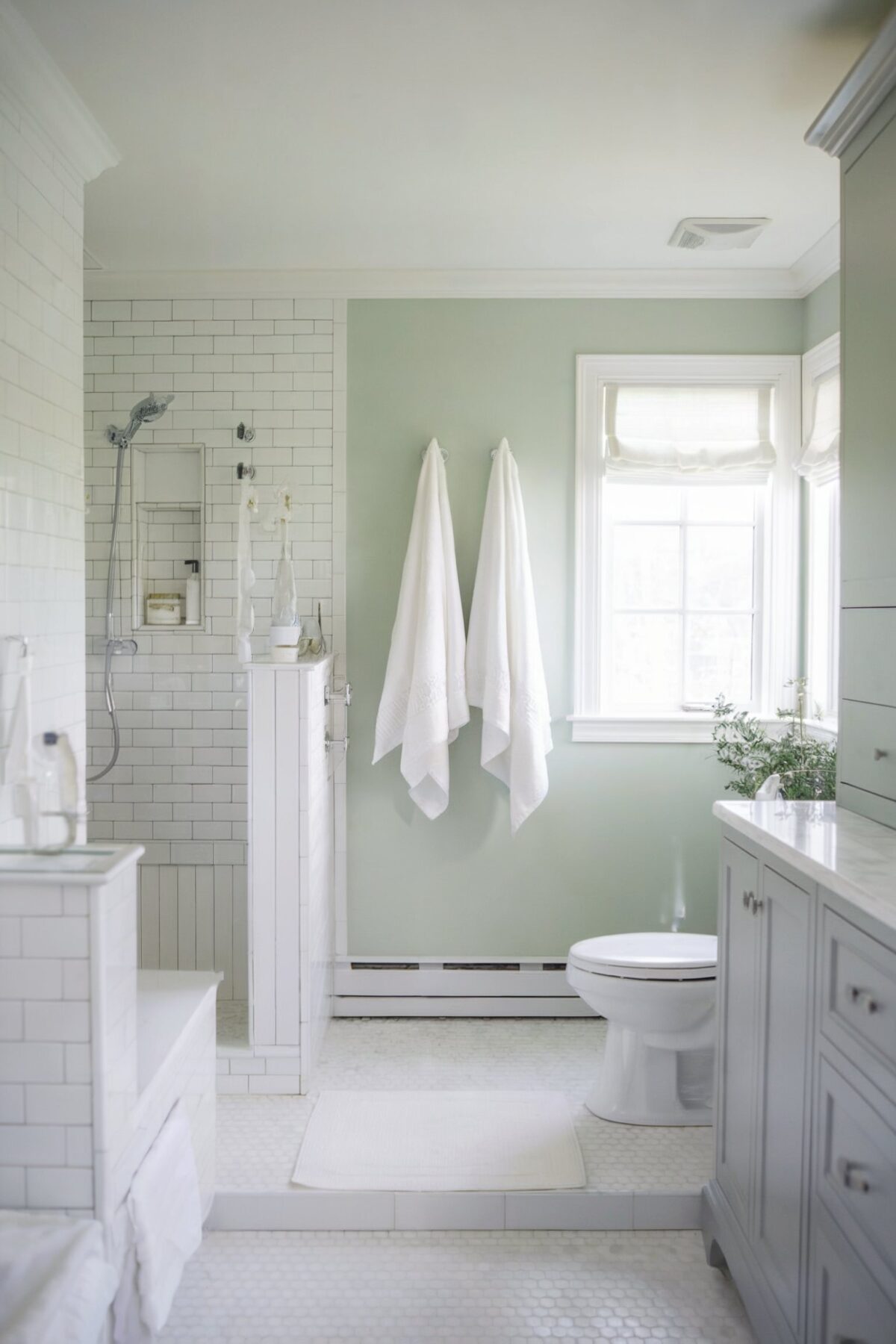 hexagon tile coastal bathroom shower wall The floor is adorned with hexagonal white tiles, and there's a gray cabinet on the right