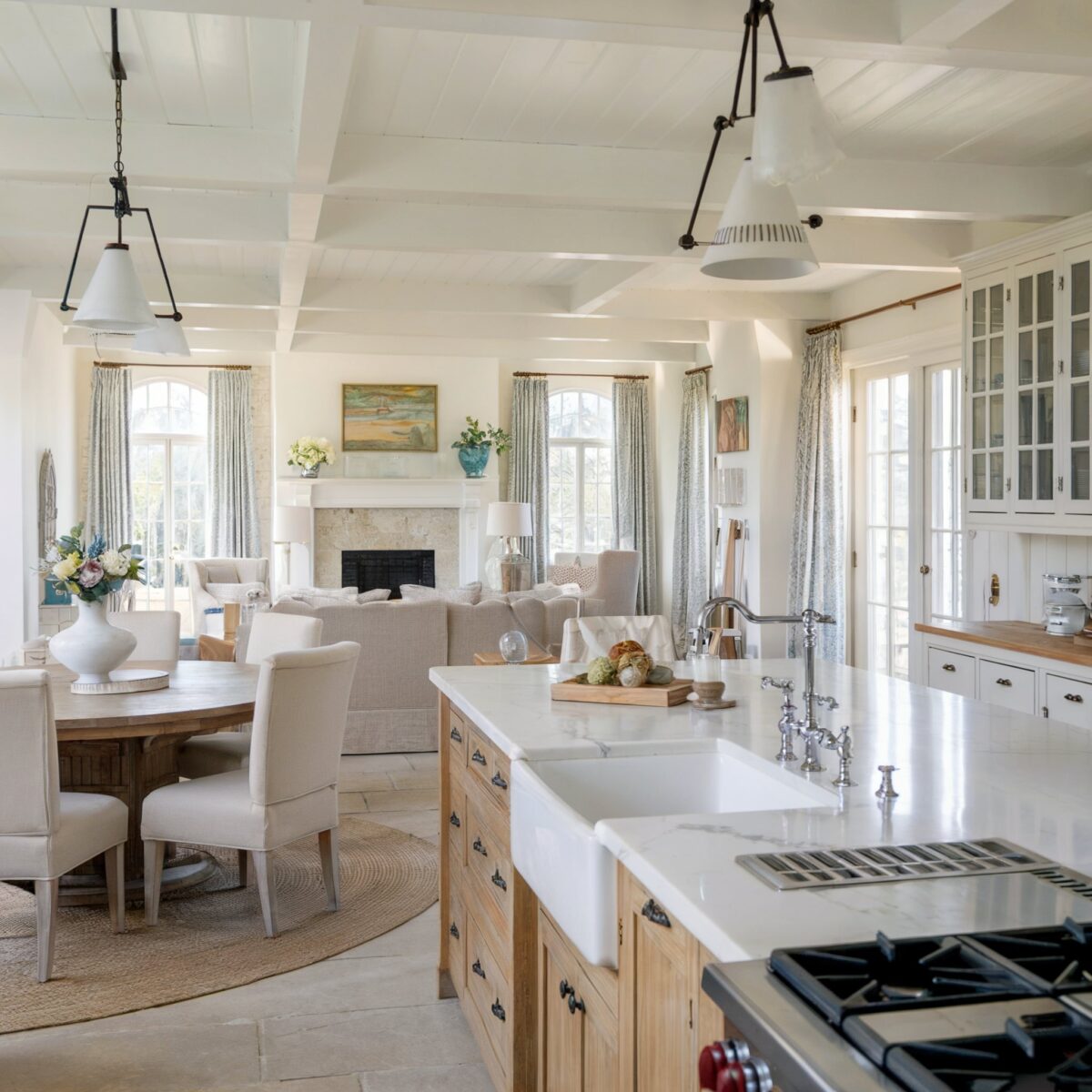 modern country kitchen open concept farmhouse style Adjacent to the kitchen is a dining area with a round wooden table surrounded by beige upholstered chairs